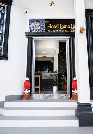 A hotel entrance with a signboard, two decorative parrots, and a marble staircase. - Loma Linda Hotel & Restaurante (Ocotal)