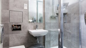 Une salle de bain moderne avec une douche à parois de verre, un lavabo blanc et des toilettes.