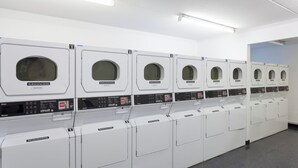 A row of white laundry machines with control panels, arranged in a clean, well-lit room. - Harrow Hall Northwick Park  (Harrow)