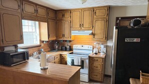 Una cucina con mobili in legno, un forno a microonde, un fornello, un frigorifero e una macchina per il caffè.