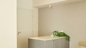 Ein modernes Interieur mit einem runden Tisch, vier Stühlen, einem Empfangstresen mit Topfpflanze und einer strukturierten Wand.