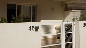 Ein modernes, zweistöckiges Gebäude mit Balkon, geschlossenem Eingangsbereich und der Hausnummer 45.