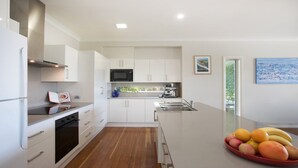 Una cocina moderna con armarios blancos, microondas integrado y cafetera.