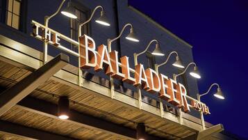 En hotellskylt med namnet ”The Balladeer Hotel”, upplyst av lampor som hänger ovanför.