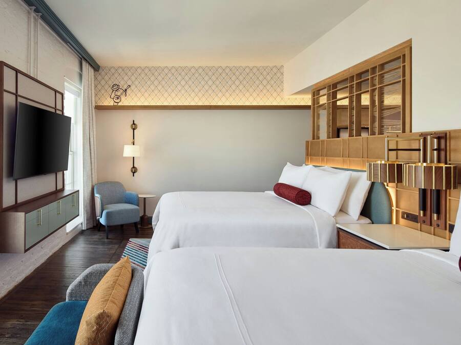 A hotel room with two beds, a TV, a desk, and a chair.