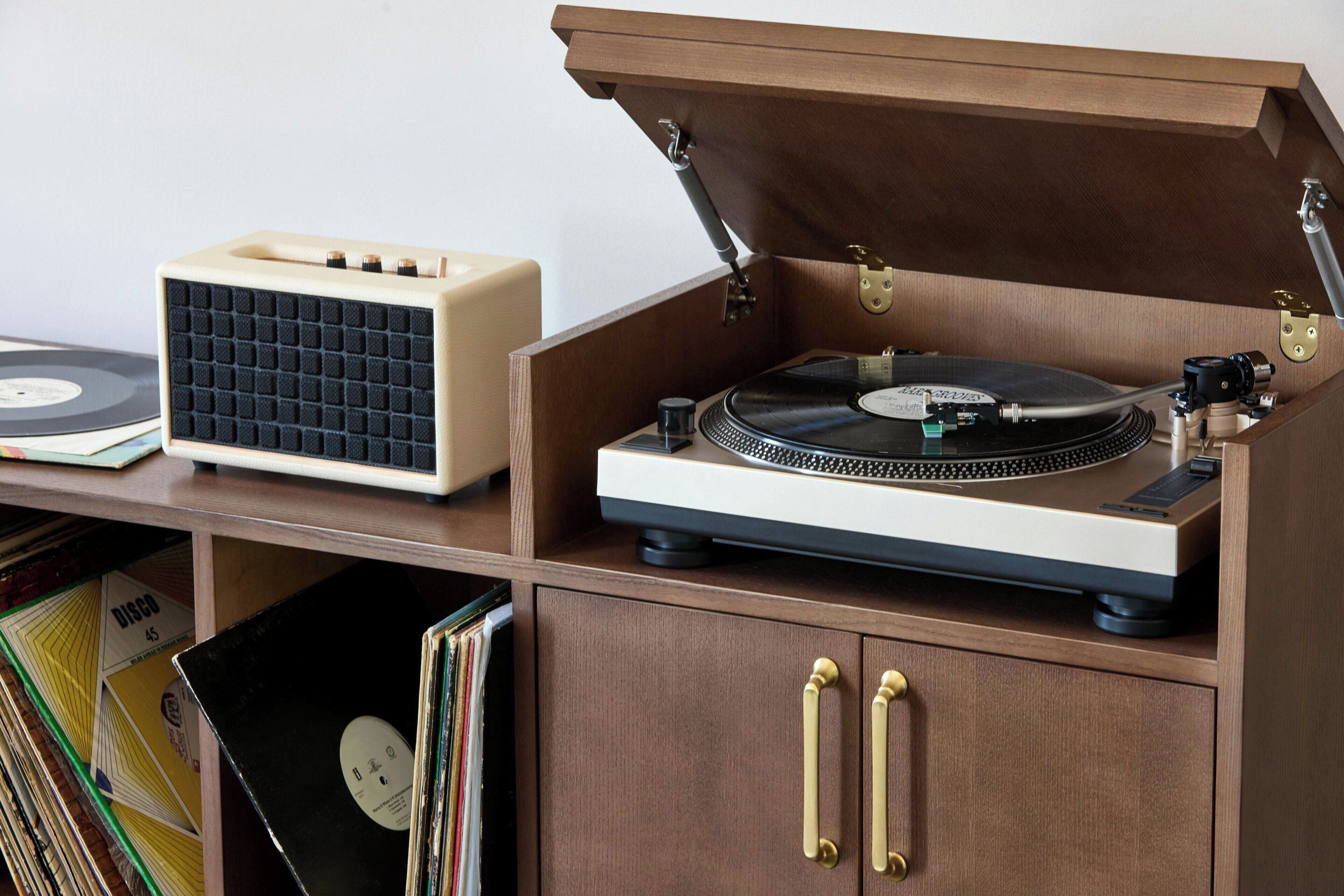 A wooden cabinet with a record player and turntable, featuring brass handles and a hinged lid.