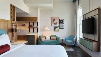 A hotel room with a bed, a sofa, a TV, a desk, and a wardrobe.
