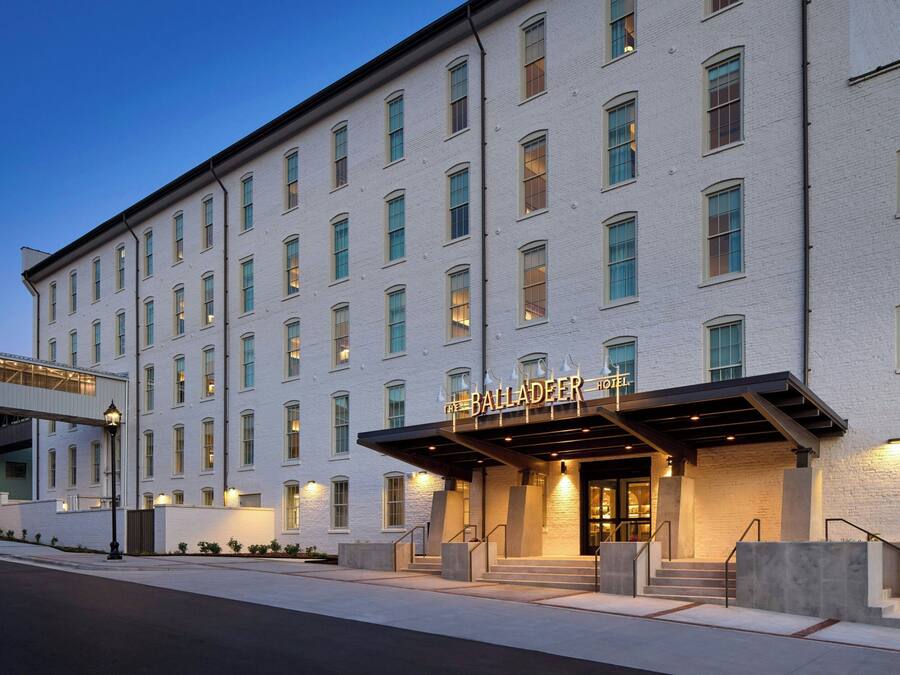 Un hotel de varios pisos con una entrada destacada, un área exterior techada y una escalera que conduce a la entrada.