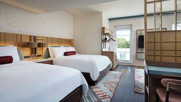 A hotel room with two beds, a desk, a chair, a TV, and a view of the outdoors.