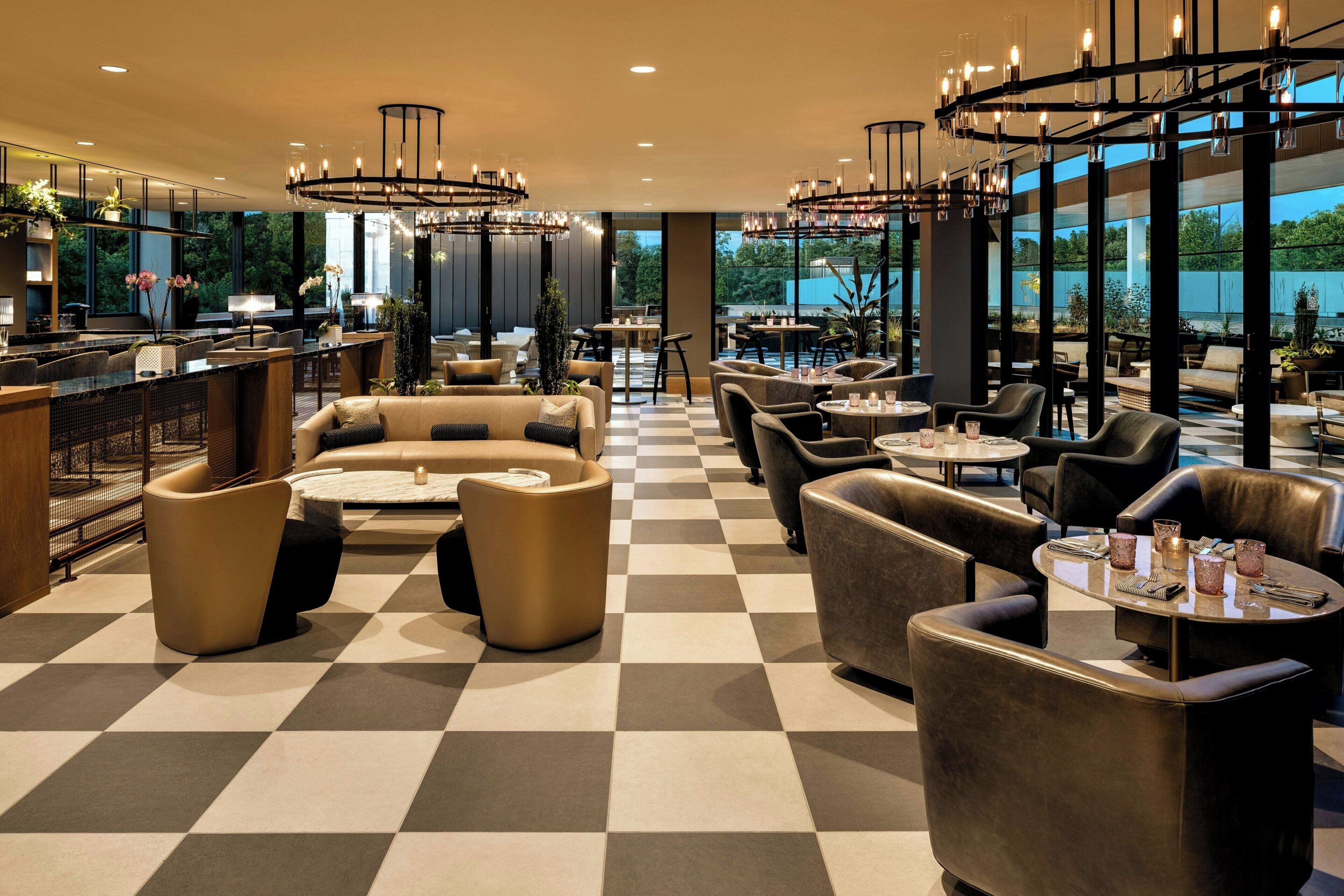 A hotel lobby with checkered flooring, leather seating, and a bar area.