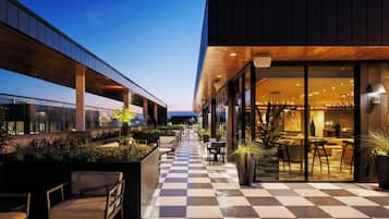 An outdoor seating area with checkered flooring, potted plants, and modern furniture.