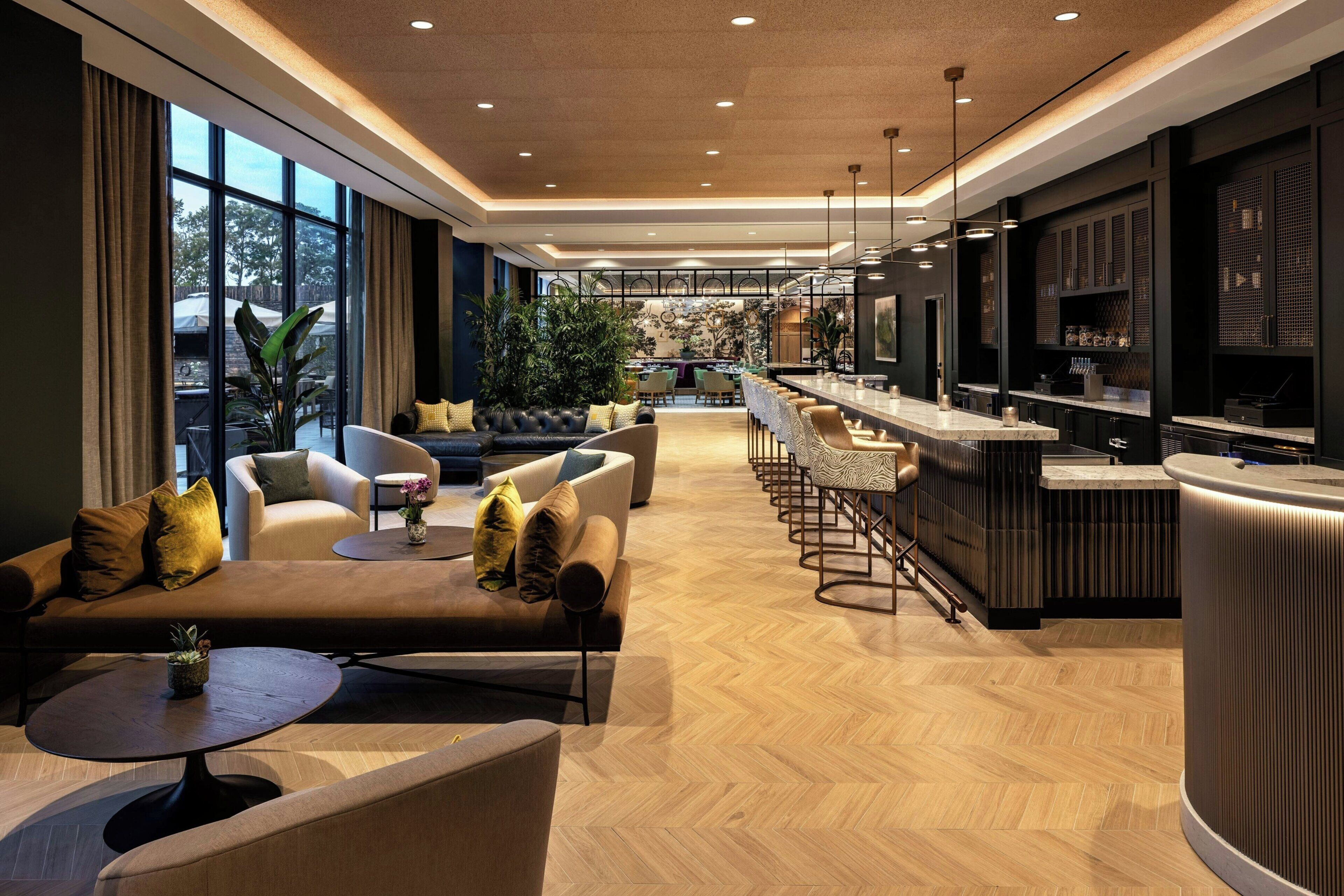 Un interior moderno con una zona de estar, un bar y vistas amplias a través de grandes ventanales.