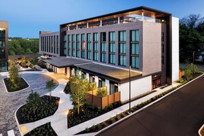 A modern building with a flat roof, large windows, and a paved courtyard with trees. - The Brandywine, Radnor, a Tribute Portfolio Hotel (Wayne)