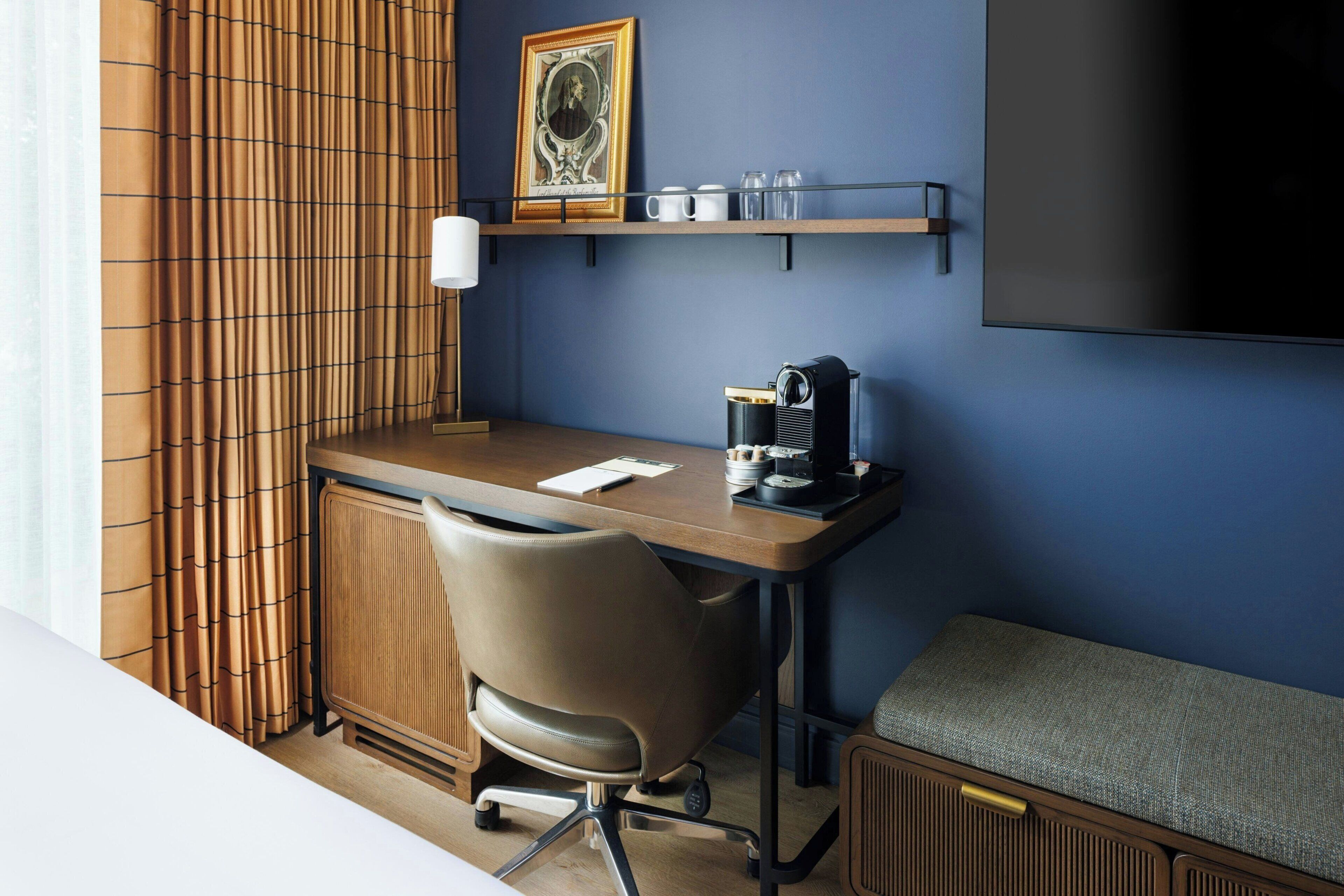 A room with a desk, chair, radiator, and a television.
