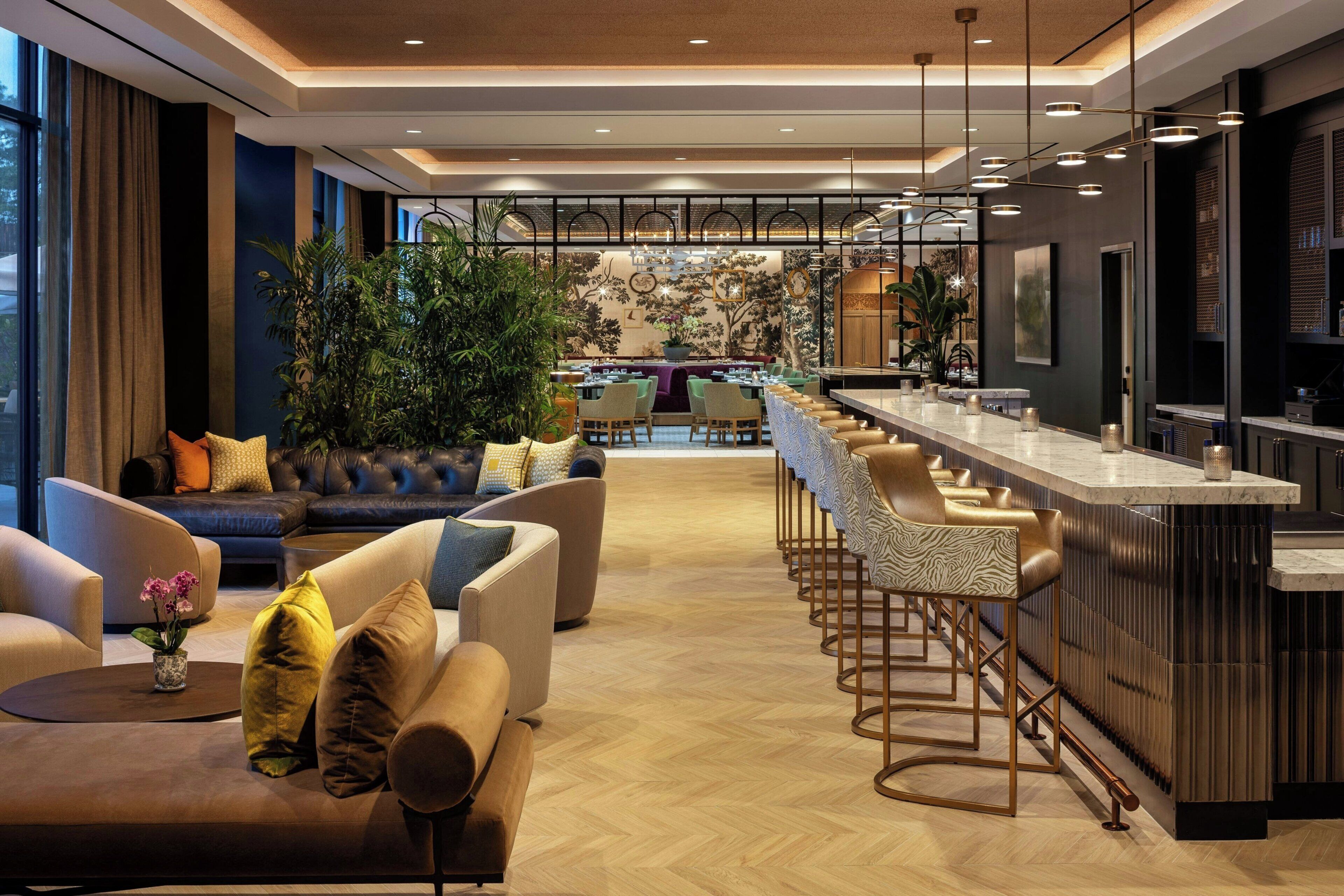 Un moderno vestíbulo de hotel con un área de descanso, un bar y vistas a la ciudad.