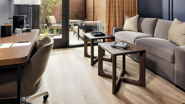 A modern living room with a wooden floor, a sofa, a coffee table, and a desk with a lamp. - The Brandywine, Radnor, a Tribute Portfolio Hotel (Wayne)