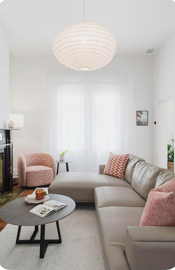 A living room with a sofa, armchair, coffee table, and a hanging light fixture.