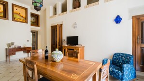 Un comedor con una mesa de madera, sillas, televisor y objetos decorativos.