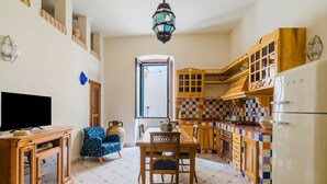 Una cocina con una mesa de comedor, sillas, un televisor y un refrigerador.