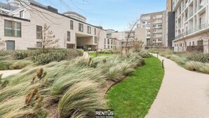 Un complesso residenziale moderno con un cortile centrale, caratterizzato da un percorso pedonale lastricato e aree verdi con erba e arbusti.