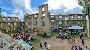 An outdoor courtyard with stone ruins, tables, and people.