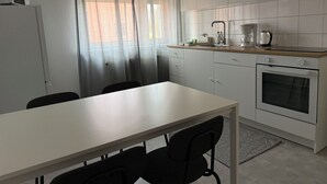 Cozinha moderna com bancada branca, forno embutido e pia.