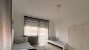 Quarto pequeno e moderno com uma cama, uma escrivaninha e um guarda-roupa.