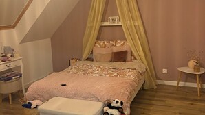 A cozy bedroom with a sloped ceiling, a canopy bed, a bedside table, a small bedside lamp, and a wall-mounted shelf. - Recent house in Séné, at the gateway to the Gulf of Morbihan, 5 minutes from the Port of Vannes (Séné)