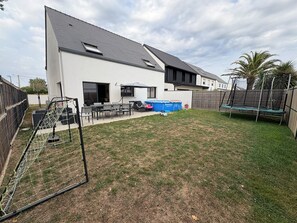 Une maison moderne avec un grand jardin, un trampoline et une piscine.