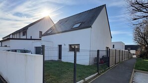 A modern building with a sloped roof, a fenced yard, and a paved pathway. - Recent house in Séné, at the gateway to the Gulf of Morbihan, 5 minutes from the Port of Vannes (Séné)