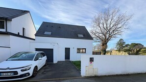 A white building with a garage, a car parked in front, and a tree in the background. - Recent house in Séné, at the gateway to the Gulf of Morbihan, 5 minutes from the Port of Vannes (Séné)