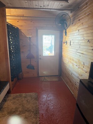 A wooden interior with a door, a fan, and a rug. - Beautiful 1-bedroom house with AC in charming Galveston (Galveston)