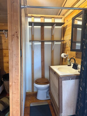 Un baño de madera pequeño y funcional con inodoro, lavabo y espejo.