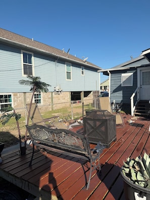 A wooden deck with outdoor furniture, a palm tree, and a house with a blue exterior. - Beautiful 1-bedroom house with AC in charming Galveston (Galveston)