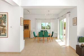 A dining area with a table and chairs, a kitchen with wooden cabinets, and a sliding glass door leading to a balcony.