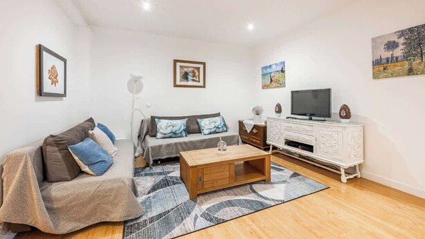 Ein Wohnzimmer mit einer Couch, einem Couchtisch, einem Fernseher und einem Schrank.
