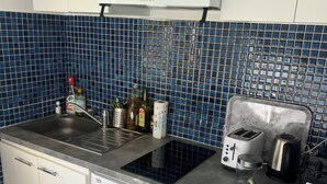 Een kleine keuken met een ingebouwde wasmachine, een magnetron en een broodrooster.