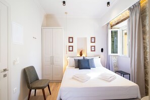 Una camera da letto con un letto, una sedia, un armadio e una finestra con tende.
