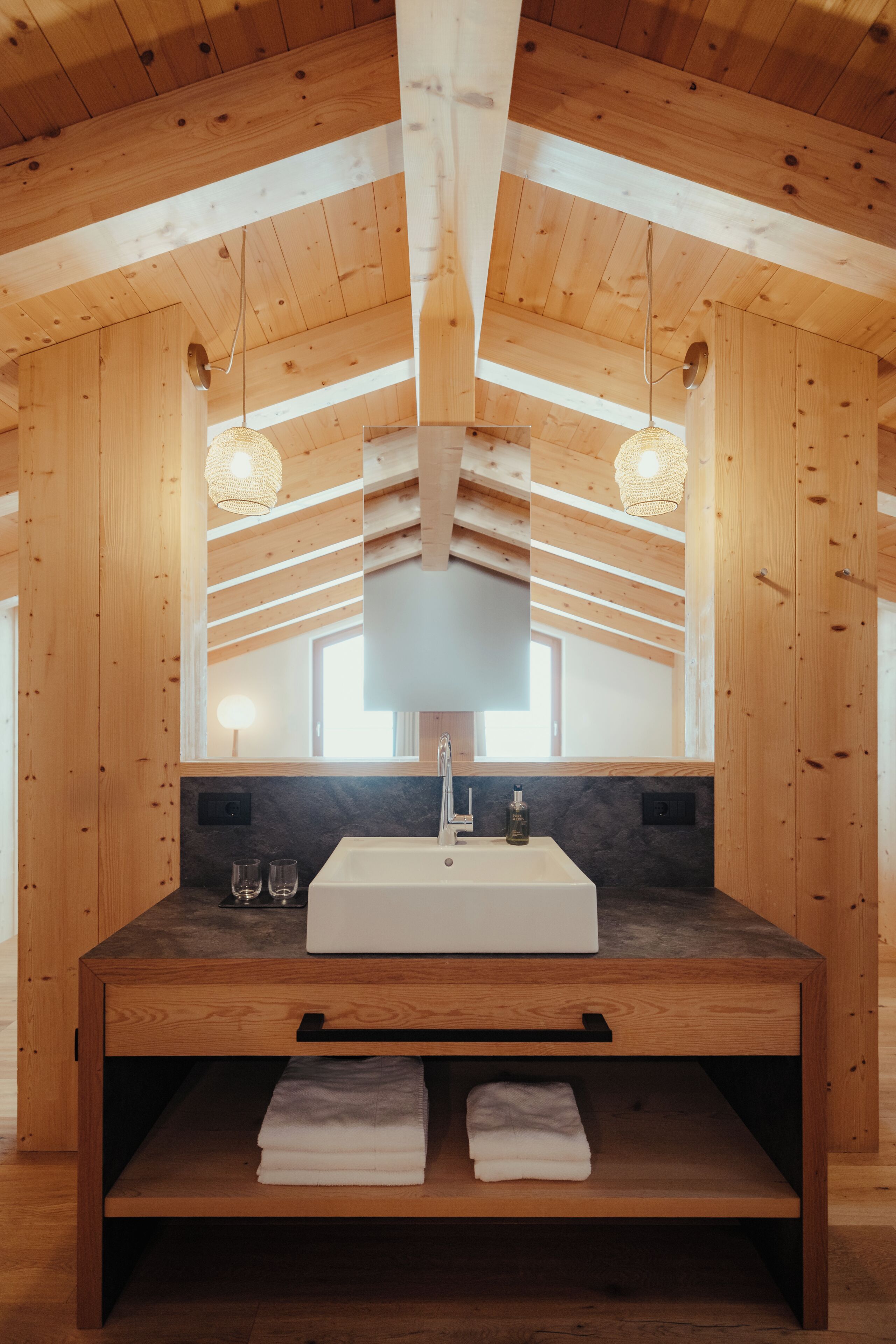 A wooden cabin interior with a large wooden vanity, a mirror, and two pendant lights.