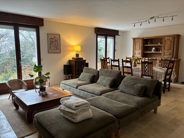 A cozy living room with a sofa, a coffee table, and a dining area with wooden chairs and a table.