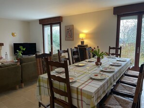 A dining area with a table set for four, surrounded by chairs, a sofa, and a television.