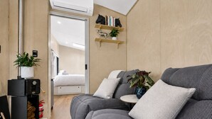 Una sala de estar moderna con un sofá gris, una mesita y una estantería con adornos.