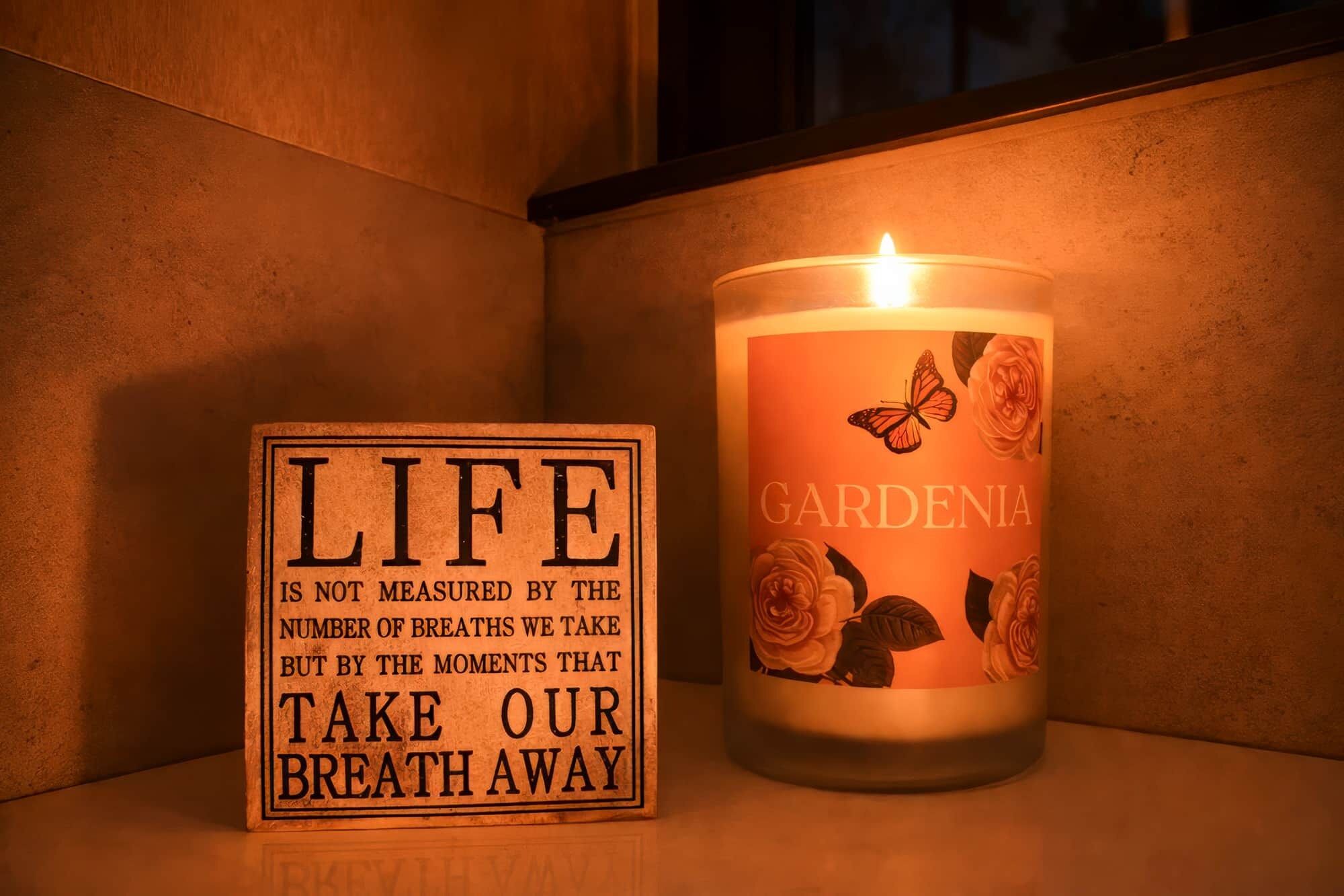 Una candela con decorazioni floreali e un cartello con una citazione sulla vita.
