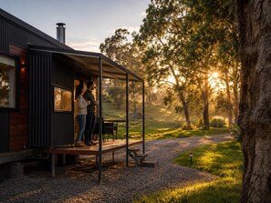 A modern building with a covered outdoor seating area, a gravel path, and trees in the background. - Crown Equine The Millstream: Escape, Unwind & Reconnect with Nature (North Dandalup)