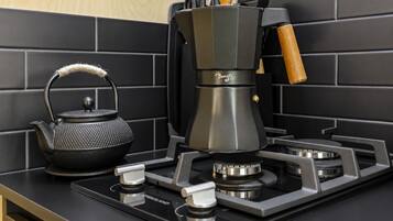 A modern kitchen with a black kettle, a coffee maker, and a gas stove.