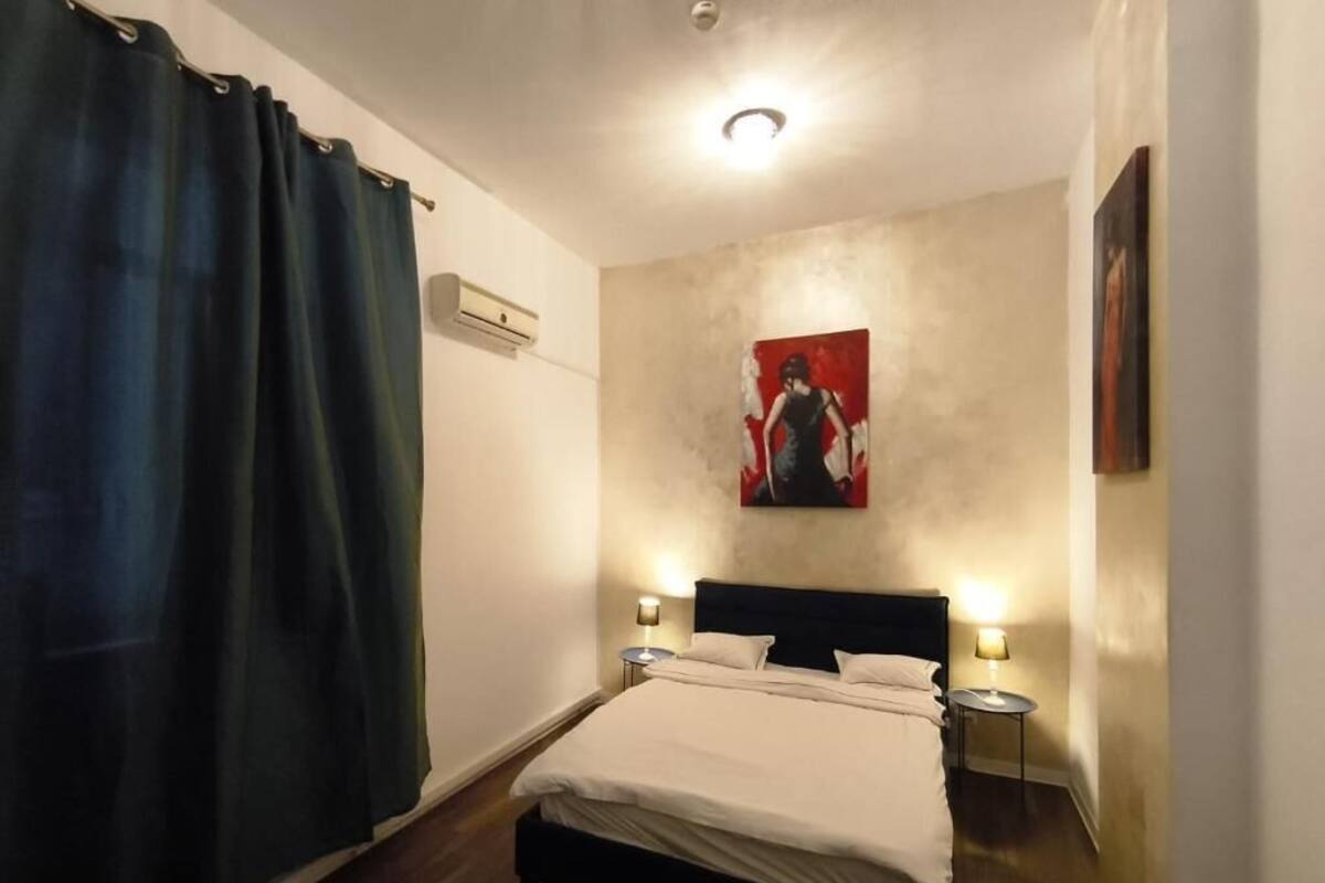 Quarto com uma cama, duas mesas de cabeceira, ar condicionado fixado na parede e um quadro.