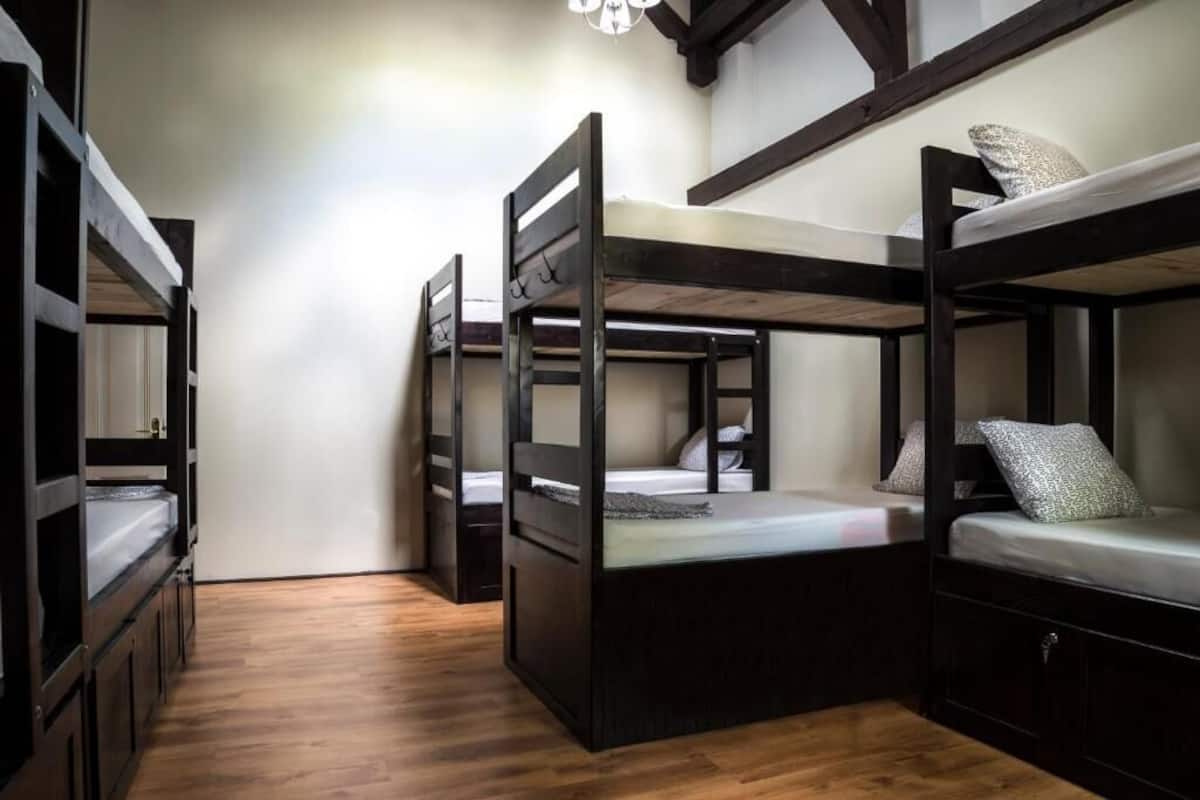 Quarto com três beliches, piso de madeira e design simples e funcional.