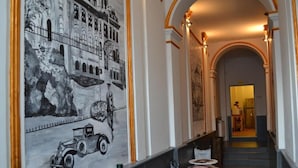 Un pasillo con un mural, techos abovedados y una escalera que lleva a una habitación.