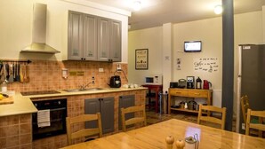 Cocina compacta con comedor, que incluye microondas, cafetera y televisión en la pared.