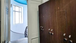 Un pasillo con un armario de madera, una puerta que da a una habitación con ventana y una lámpara de techo roja.